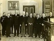 Photographie noir et blanc de quatorze hommes debout.