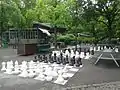 Jeux d’échecs avec, à l'arrière-plan, le restaurant du parc