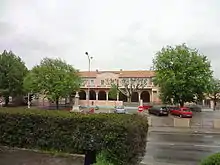 La façade de l'école, peinte en rose, est composée du préau ouvrant par des arcades sur la cour, surmonté d’un étage de fenêtres des salles de classe