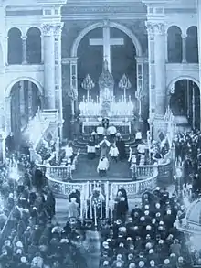vue plongeante d'une cérémonie funéraire dans une grande église avec prélats et fidèles recueillis devant un cercueil.