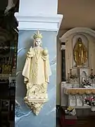 Une statue de l'Enfant Jésus de Prague. À droite la Chapelle de la Vierge Marie