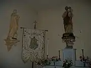 À droite saint Joseph tenant dans ses bras l'Enfant Jésus, à gauche saint Jean l'évangéliste, au centre l'Assomption de Marie broder sur un tissu.