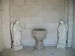 Une ancienne cuve baptismale en pierre entourée de deux statues d'anges