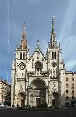 Photographie couleur montrant la façade d'une église, surmontée de deux flèches dissymétriques