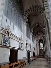 Photographie couleur d'un bas-côté d'église assez sombre.