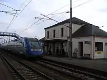 Le bâtiment voyageurs, les voies, les quais, la passerelle et un train TER.