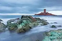 Photographie numérique couleur d'une île sur laquelle est construite une tour d'allure sarazinne.