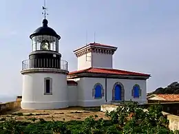 Photographie en couleur d'un phare avec son bâtiment attenant pour les gardiens.