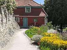 Photo en couleur d'une maison rouge avec jardin fleuri en terrasse