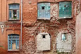 Les briques de la façade tombent ; des fenêtres sont murées.