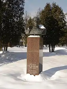 Photo en couleur d'un buste au milieu d'un parc sous la neige.