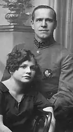 Photo noir et blanc d'un homme en uniforme debout et d'une femme assise.