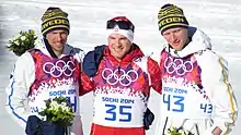 Trois skieurs posant pour les photgraphes, celui du centre tenant par les bras les deux autres.