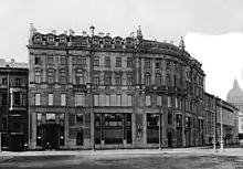 Photographie en noir et blanc d'un immeuble à colonnades formant l'angle d'une rue