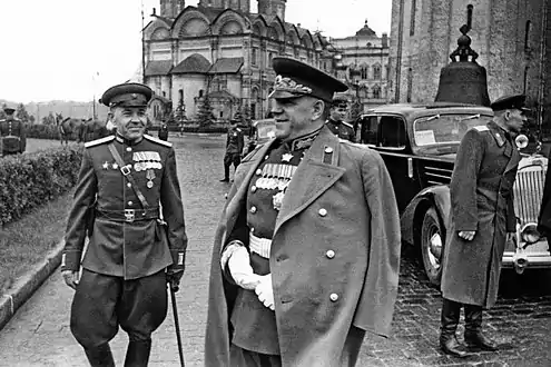 Photo noir et blanc de trois hommes en uniforme, les poitrines bardées de médailles, près d'une automobile.