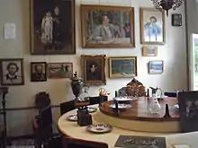 Photographie d'un intérieur bourgeois, des tableaux sont accrochés aux murs.