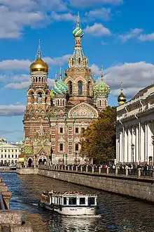 "Photographie de la cathédrale le long du canal Griboïedov. Un bateau-mouche passe au premier plan."