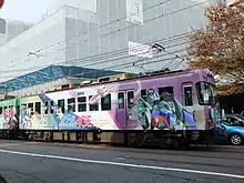 Premier wagon d'un train peint avec un robot Gundam sur la droite et plusieurs personnages sur la gauche.