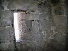 intérieur aux murs en blocs de pierre gris-bleu, ouverture en fente