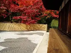 Wooden building with an open veranda next to a raked gravel garden.