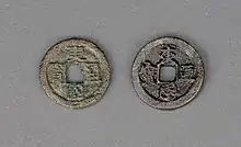 Photographie de deux pièces de monnaies, chacune posées sur des faces différentes. Elle sont posée sur un présentoir.