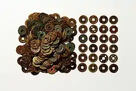 Photographie de pièces de monnaie. Un tas de pièces sont visibles sur la moitié gauche, alors qu'à droite les pièces sont alignées sur 4 colonnes et 6 rangées.