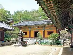 photographie d'un sanctuaire, trois bâtiments sont visibles sur les trois cotés d'un cour. Une statue est visible en son centre.