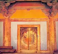 Photographie d'une porte à l'intérieur d'un temple. Celle-ci est fermée et dotée de peintures décoratives.