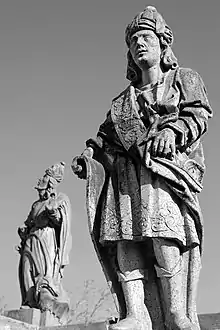 Photographie en noir et blanc. Deux statues : la première au premier plan représente Baruch, richement vêtu et portant un grand parchemin ; la deuxième, en arrière-plan, représente Jonas regardant vers le ciel.
