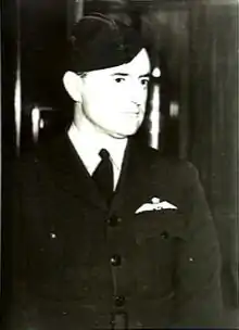 Portrait en noir et blanc d'un homme en uniforme militaire sombre et coiffé d'un chapeau de fourrage