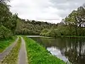 L'Aulne (Canal de Nantes à Brest) au nord-est de l'écluse de Rosili (écluse n° 213, en Châteauneuf-du-Faou) ; en haut du versant, à l'arrière-plan, le domaine touristique de Méros (en Plonévez-du-Faou).