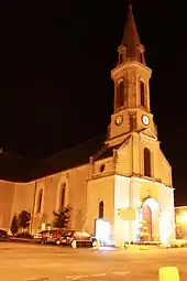 L'église de l’Immaculée Conception éclairée par les lampadaires, vue de trois-quart gauche