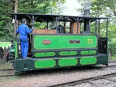 Locomotive à vapeur de tramway équipée d'une toiture et d'un mécanisme masqué par des tôles.