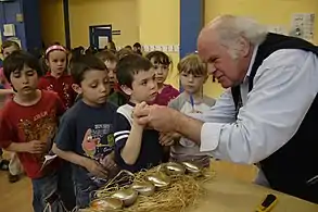 L'artiste Jocelyn Maltais examine les éléments apportés par les élèves pour les déposer dans les œufs d'or.