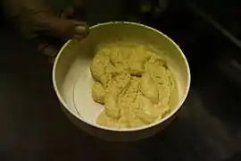 photo couleur d'un plat contenant une pâte jaune pâle granuleuse de consistance épaisse.