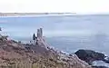 Le rocher du « Doigt de Dieu » et, en arrière-plan, la côte de Moëlan-sur-Mer.
