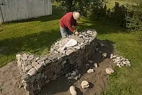 L'artiste Jocelyn Maltais plaçant quelques roches dans le Tacon Site de la Famille.