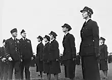 Photo en noir et blanc montrant des hommes et des femmes en costume militaire sombre.