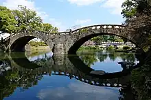 Photo couleur d'un pont de pierre à deux arches.