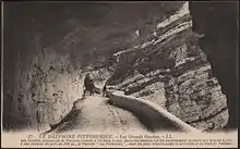 Carte postale en noir et blanc d'une route en encorbellement taillée dans la roche au sein de gorges vertigineuses
