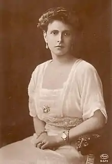 Photographie en noir et blanc d'une jeune femme assise portant une robe blanche.