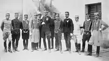 Photographie en noir et blanc représentant douze hommes en uniforme posant fièrement devant un bâtiment.