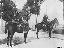 Photo noir et blanc de deux cavaliers isolés, l'un observant au loin avec ses jumelles.