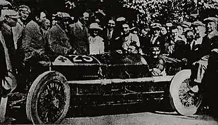 Photo d'un homme au volant d'une voiture, entouré par la foule.