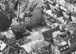 Vue aérienne de la façade arrière du bâtiment historique et de la cour avec fontaine, en avril 1935.