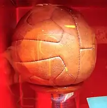 Photographie du ballon officiel de la compétition, de couleur marron, vu en gros plan.