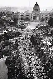 Photo aérienne noir et blanc d'un carrefour de deux avenues bordées par des arbres, dans lesquelles est rassemblée une foule immense. Le bâtiment de l'assemblée nationale forme l'arrière-plan de l'image.