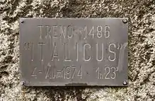 Image d'une plaque couleur bronze gravée d'un texte, fixée sur un mur.
