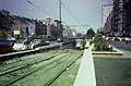 Un tram 18 en direction de  Fort Jaco sort du prémétro sur l'avenue de la Toison d'or et arrive à la place Louise. Il croise un tram 32 barré en direction de Jette avec en arrière-plan la porte de Namur (1985)