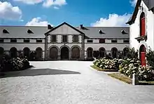 Bâtiment de style napoléonien avec des massifs de fleurs.